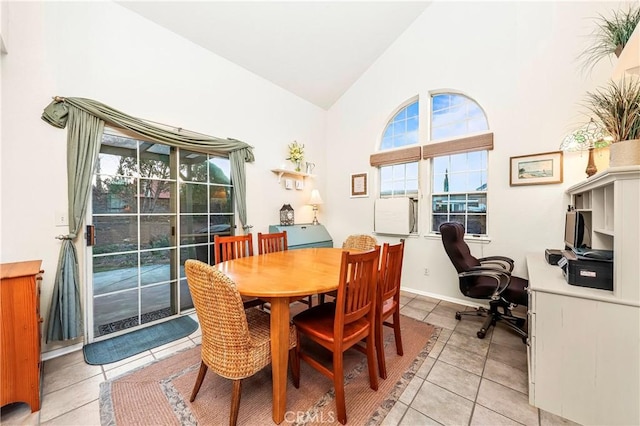 dining space with light tile patterned floors, high vaulted ceiling, and baseboards