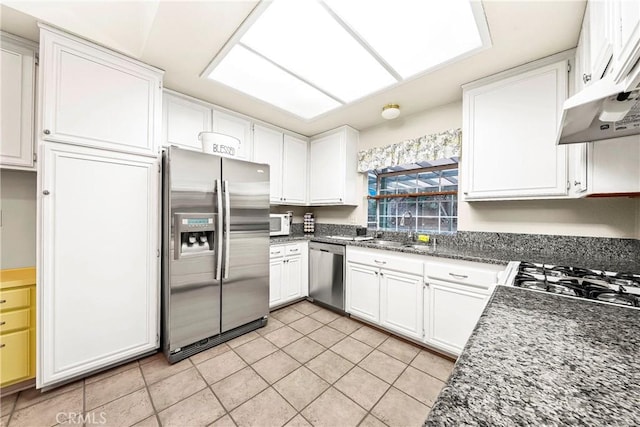 kitchen with a sink, under cabinet range hood, white cabinetry, stainless steel appliances, and light tile patterned floors