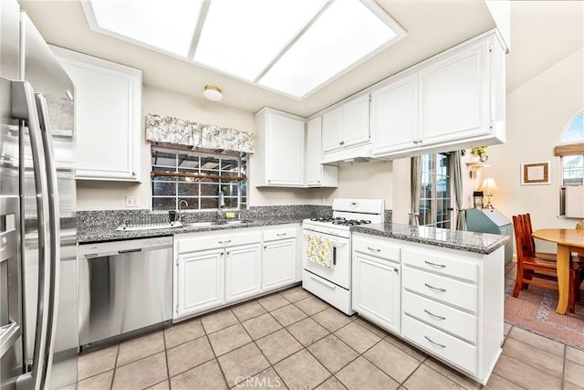 kitchen featuring white cabinetry, a skylight, a wealth of natural light, and stainless steel appliances