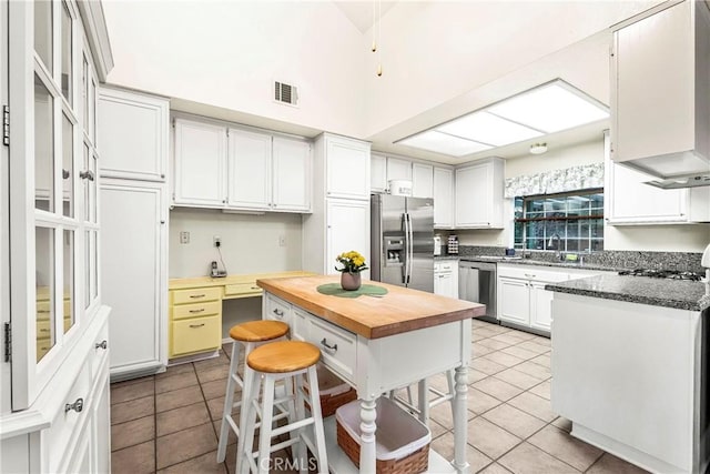 kitchen featuring visible vents, butcher block countertops, light tile patterned floors, appliances with stainless steel finishes, and white cabinets