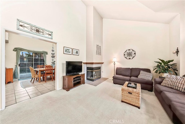 carpeted living area with a multi sided fireplace, tile patterned flooring, and a towering ceiling