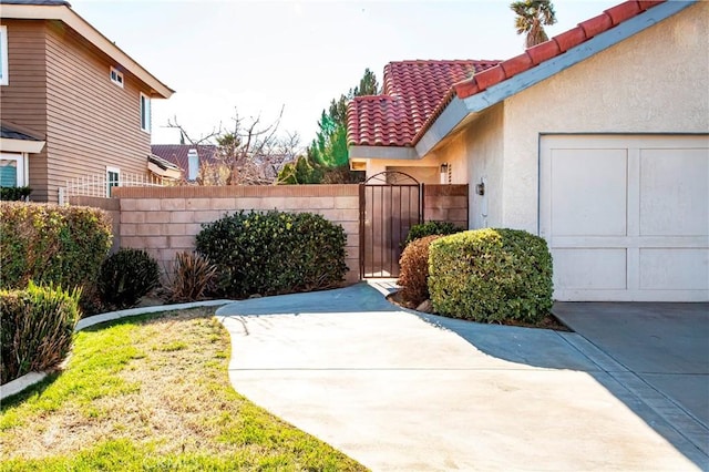 view of side of home featuring a gate, stucco siding, a tile roof, and fence