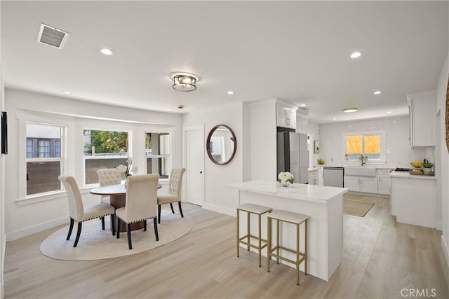 dining room featuring light wood-type flooring, visible vents, plenty of natural light, and recessed lighting