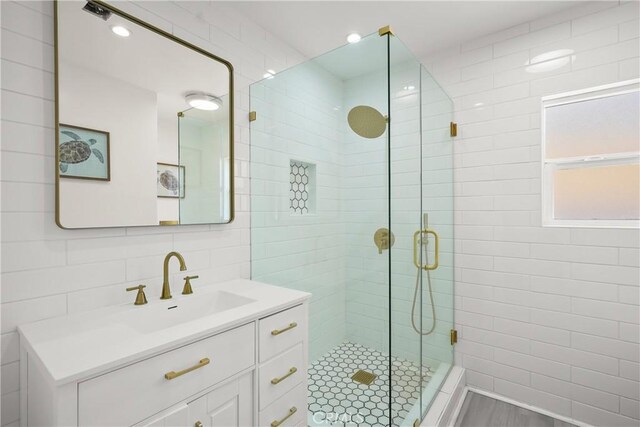 full bathroom featuring backsplash, a stall shower, tile walls, and vanity