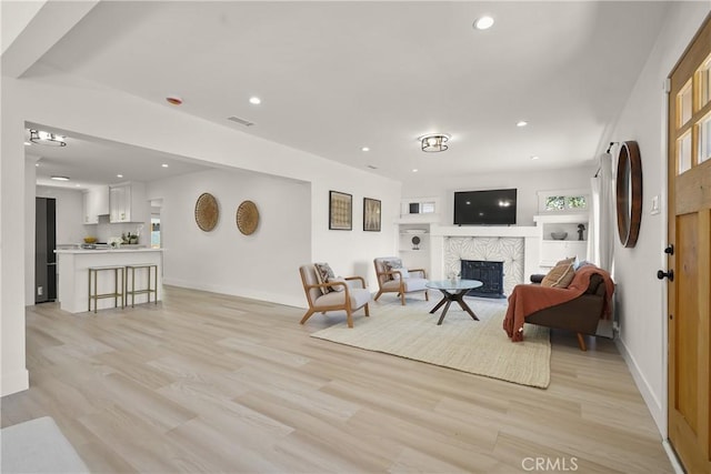 living room with recessed lighting, baseboards, light wood-style flooring, and a fireplace