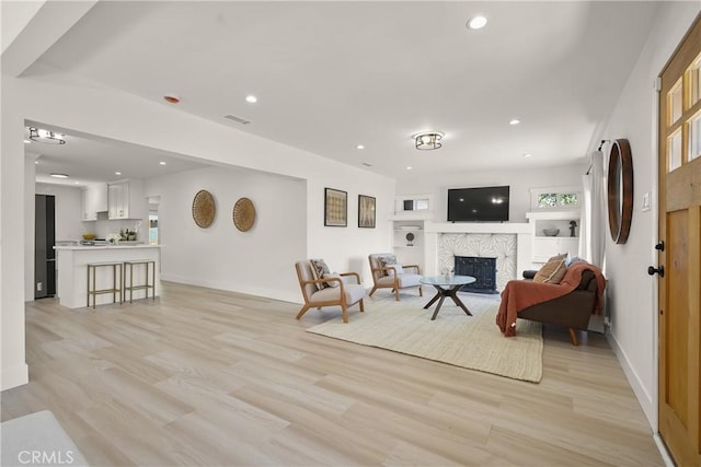 living area featuring recessed lighting, baseboards, light wood-style flooring, and a fireplace