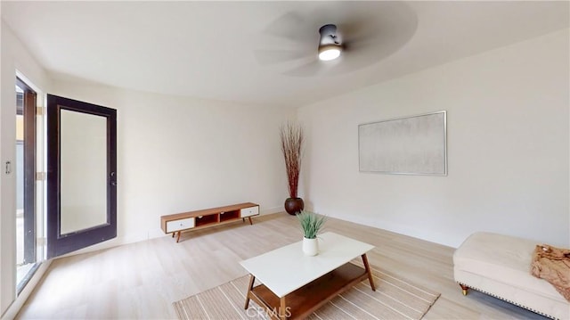 living area with a healthy amount of sunlight, ceiling fan, and wood finished floors