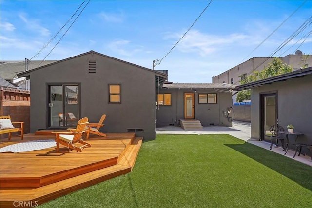 back of house featuring visible vents, a wooden deck, stucco siding, crawl space, and a lawn