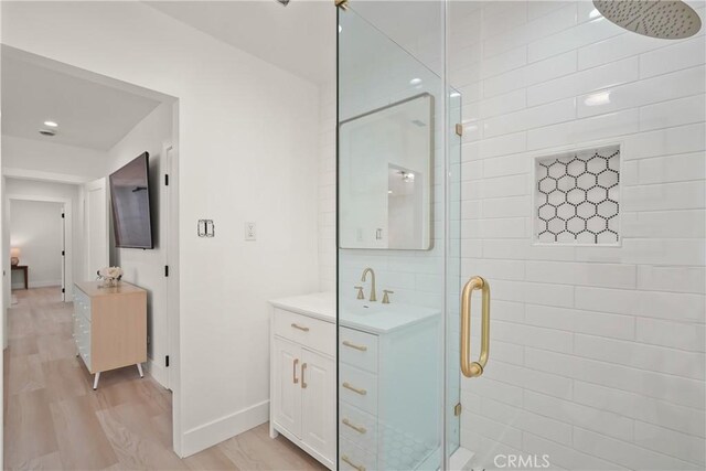 bathroom with a stall shower, vanity, baseboards, and wood finished floors