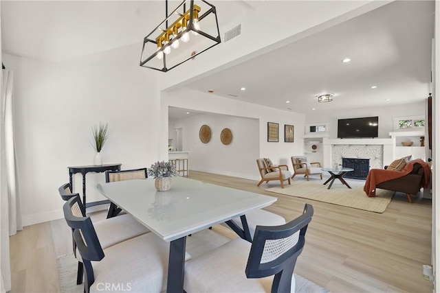 dining room with recessed lighting, visible vents, light wood-type flooring, and a premium fireplace