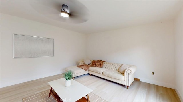 living area featuring ceiling fan, baseboards, and wood finished floors