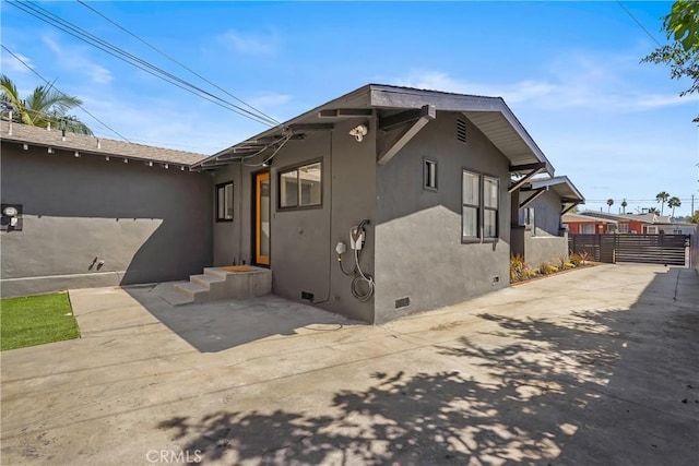 view of side of property featuring a patio area, crawl space, stucco siding, and fence