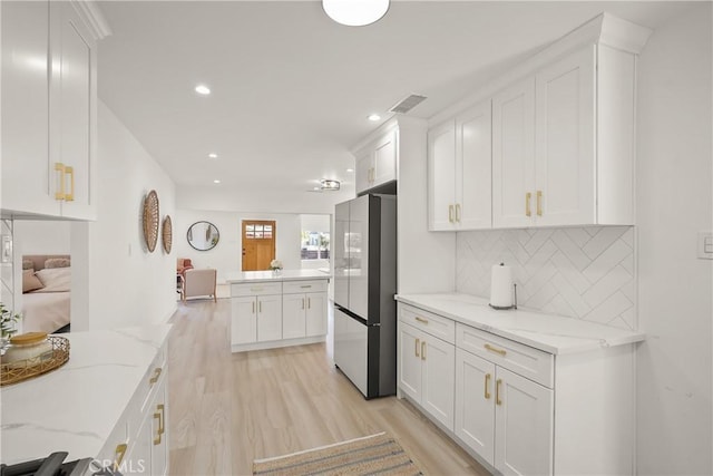 kitchen with white cabinetry, light wood-style flooring, visible vents, and freestanding refrigerator