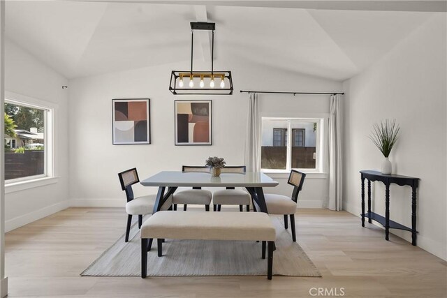 dining area with lofted ceiling, light wood-style flooring, and baseboards