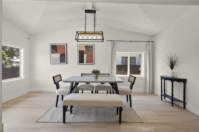dining space with lofted ceiling, baseboards, and light wood-type flooring