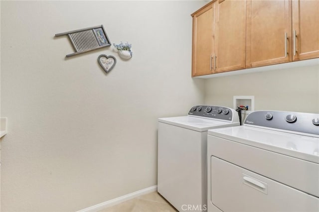 laundry area with light tile patterned floors, baseboards, cabinet space, and washing machine and dryer