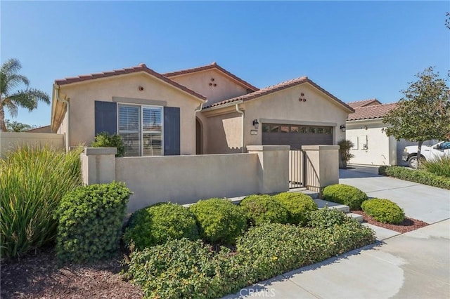 mediterranean / spanish-style house featuring an attached garage, driveway, a fenced front yard, and stucco siding