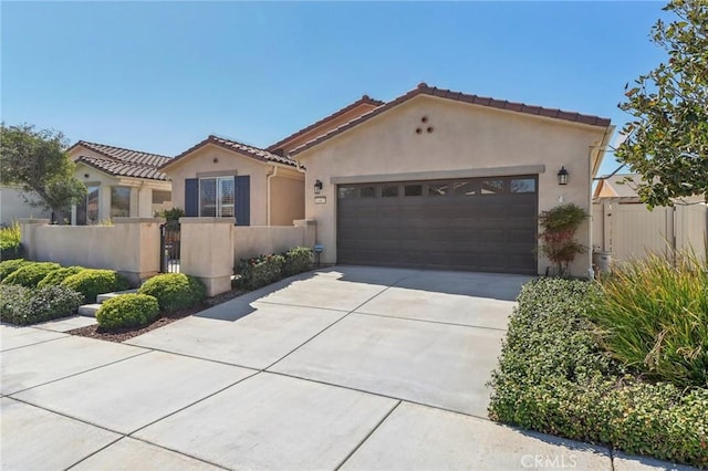 mediterranean / spanish-style house with a gate, a garage, a fenced front yard, and stucco siding