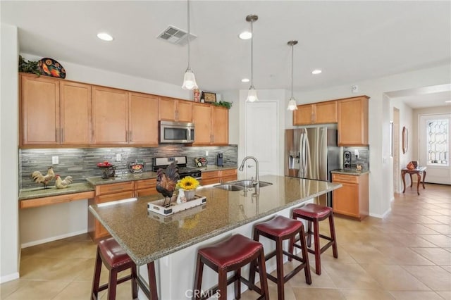 kitchen featuring a breakfast bar area, visible vents, a sink, decorative backsplash, and stainless steel appliances