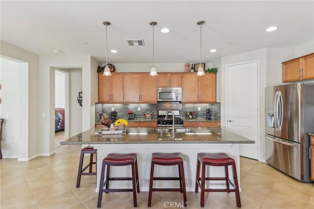 kitchen featuring visible vents, a sink, backsplash, appliances with stainless steel finishes, and a breakfast bar area