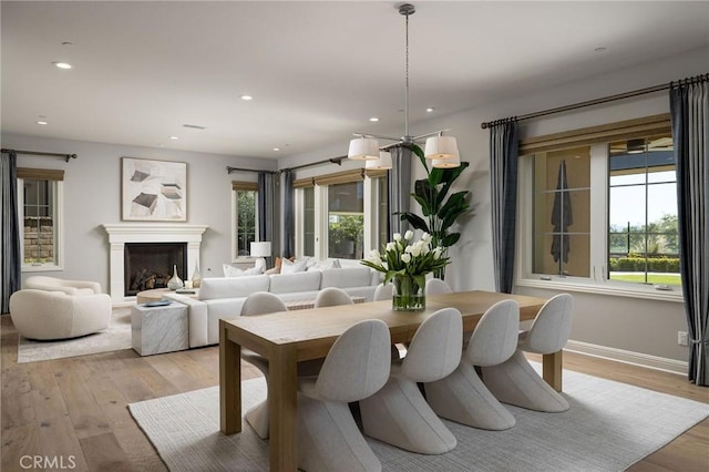 dining space featuring recessed lighting, a fireplace, baseboards, and light wood finished floors