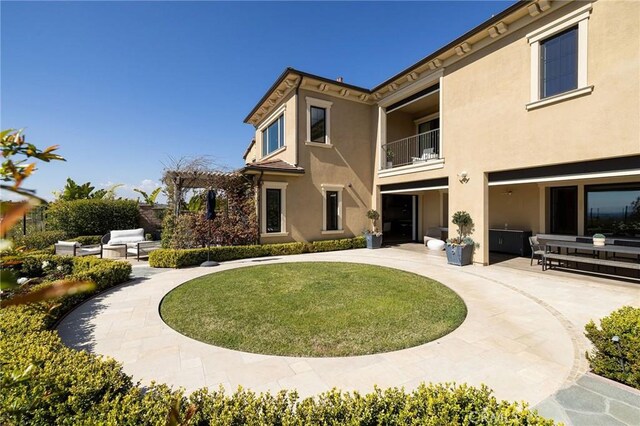 back of house with a yard, stucco siding, a pergola, and a patio