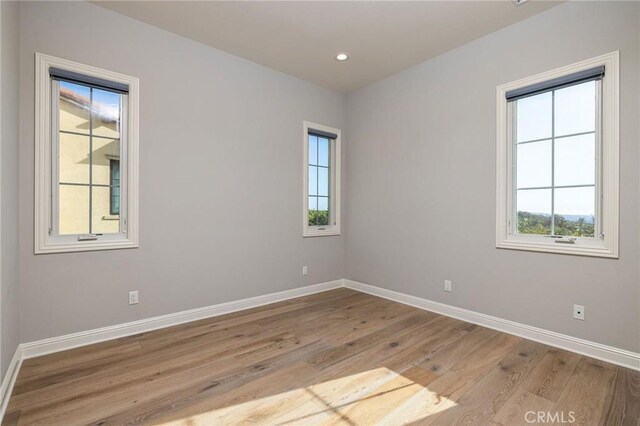 spare room with recessed lighting, light wood-type flooring, and baseboards