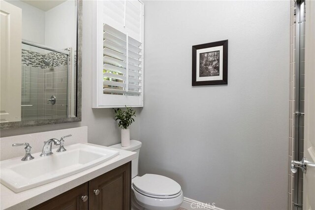 full bathroom featuring tiled shower, toilet, and vanity