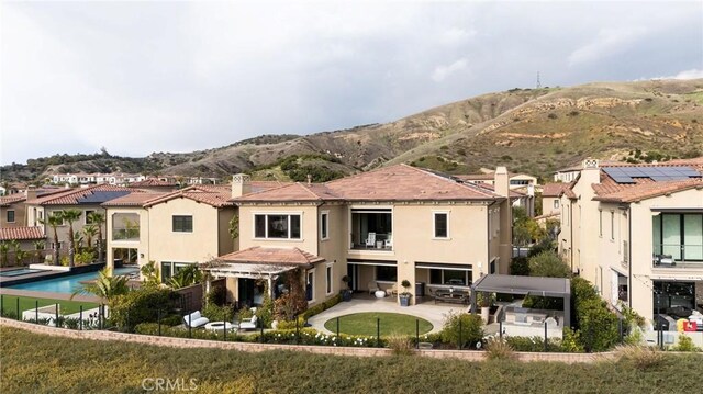 rear view of house with a residential view, a chimney, stucco siding, a patio area, and a mountain view