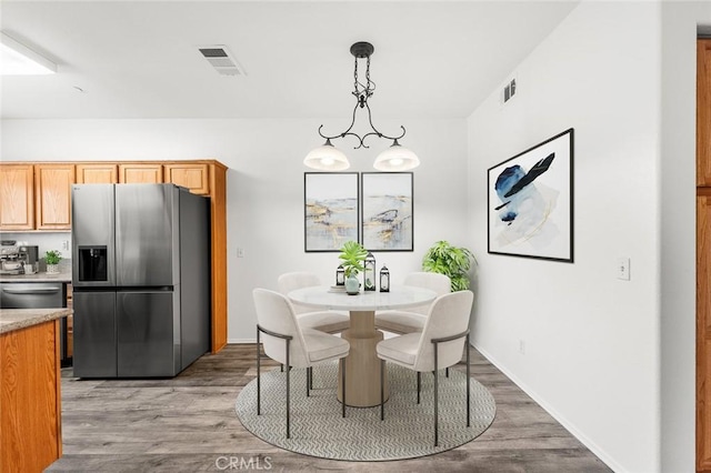 dining area featuring visible vents, baseboards, and wood finished floors