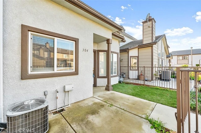 rear view of property with stucco siding, cooling unit, and fence