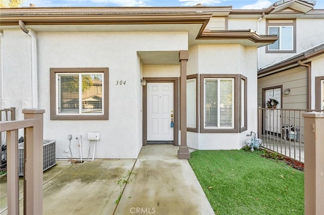 doorway to property featuring stucco siding and fence