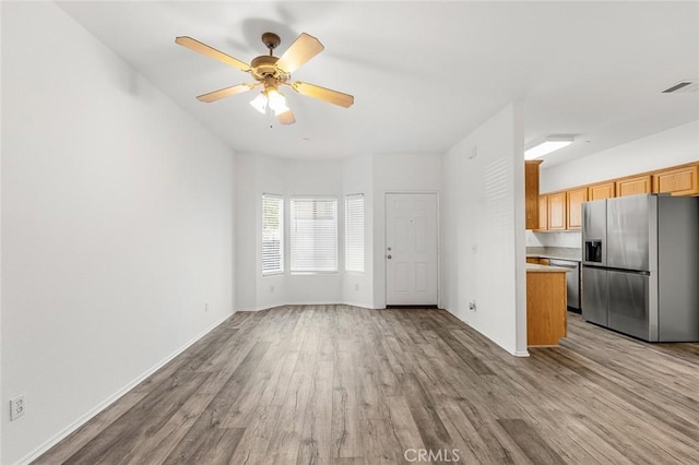 unfurnished living room with visible vents, light wood-style floors, baseboards, and ceiling fan