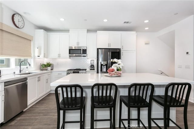 kitchen featuring dark wood finished floors, white cabinetry, stainless steel appliances, and a sink