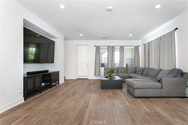 living area with recessed lighting, wood finished floors, visible vents, and baseboards