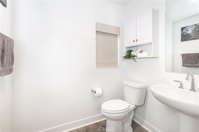 bathroom with wood finished floors, toilet, baseboards, and a sink