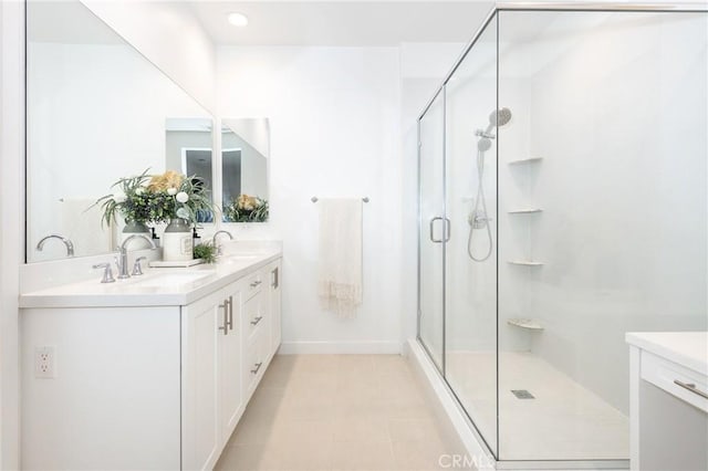 full bath featuring double vanity, baseboards, a stall shower, and a sink