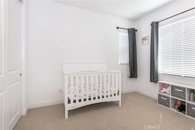 carpeted bedroom with a crib and baseboards