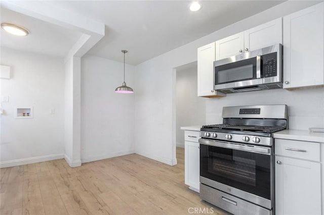 kitchen with baseboards, light countertops, light wood-style flooring, appliances with stainless steel finishes, and white cabinets