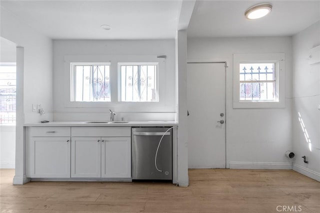 kitchen featuring light wood-style flooring, dishwasher, light countertops, and a sink