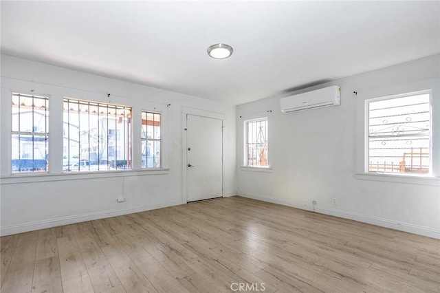 empty room with wood finished floors, a healthy amount of sunlight, and a wall mounted AC