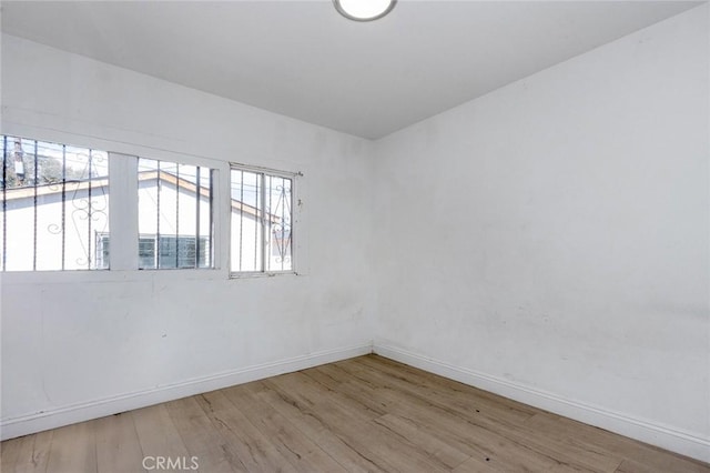 spare room with baseboards and wood finished floors