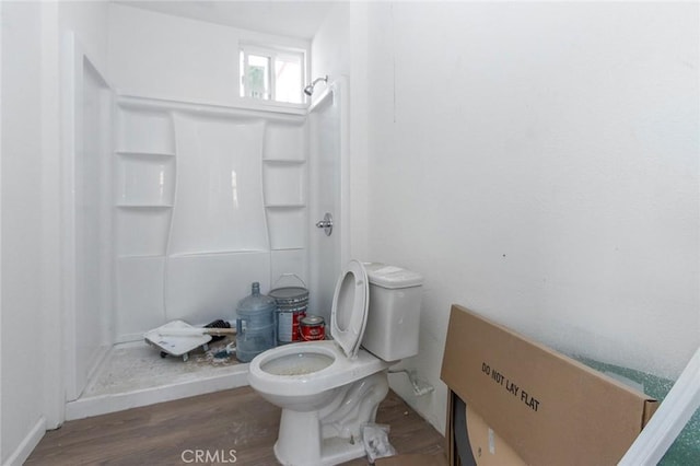 bathroom featuring toilet, wood finished floors, and a stall shower