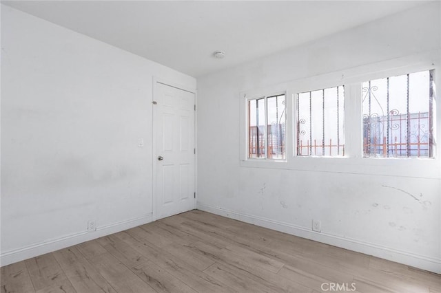 spare room with baseboards and wood finished floors