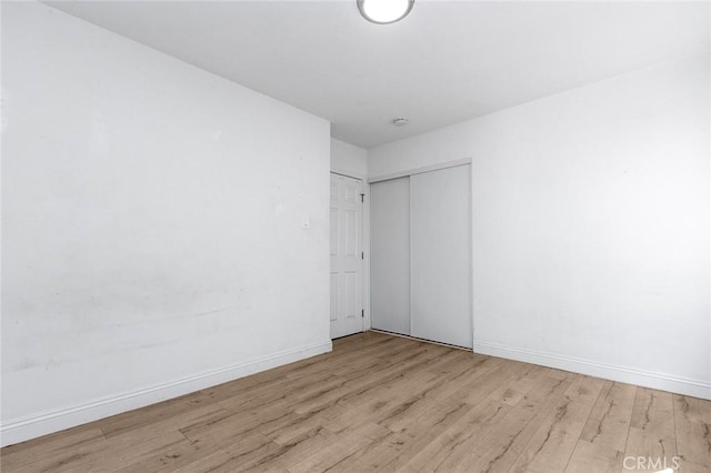 spare room with baseboards and wood finished floors