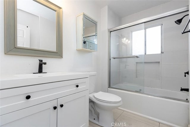 full bath featuring tile patterned flooring, toilet, vanity, and bath / shower combo with glass door