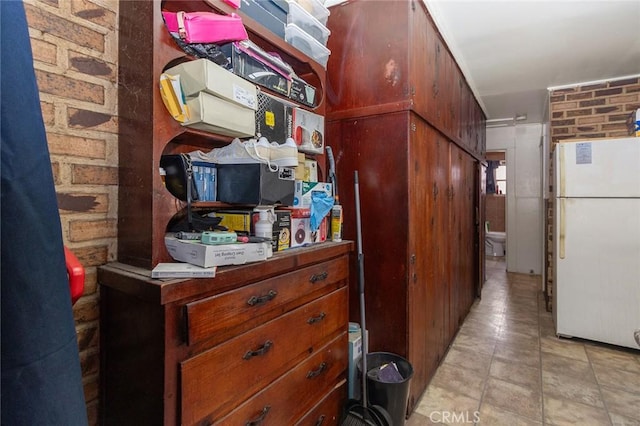 kitchen with brick wall and freestanding refrigerator