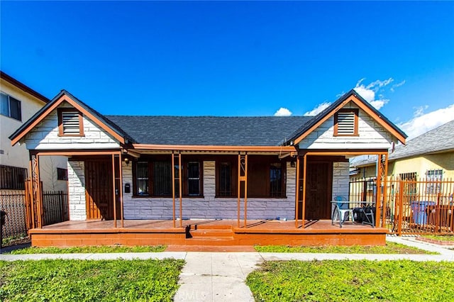 view of front facade with roof with shingles and fence