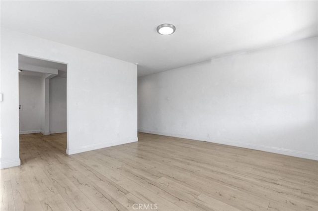 spare room featuring light wood finished floors and baseboards