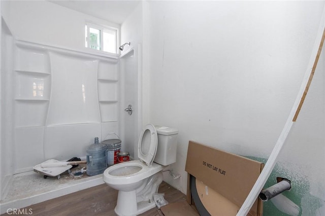 bathroom featuring wood finished floors, toilet, and a stall shower